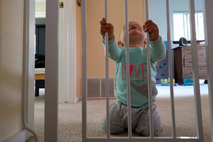 Baby behind a baby gate.